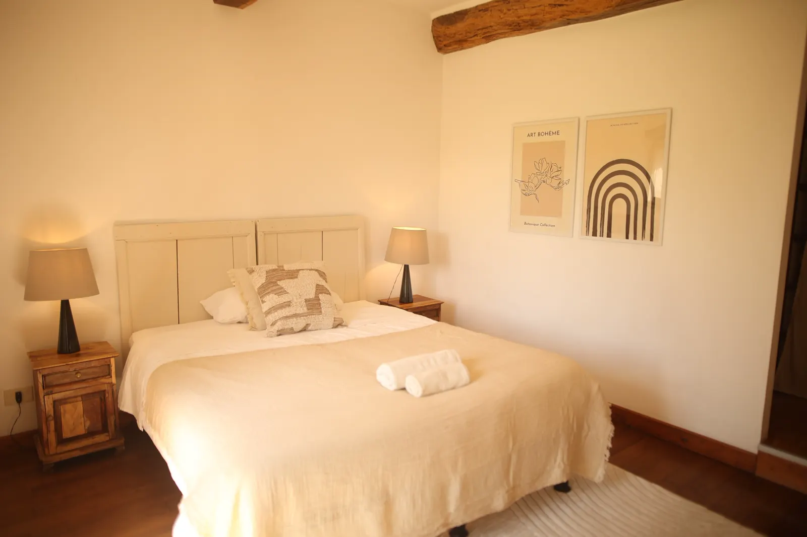 Zimmer mit Doppelbett, Nachttischlampen und Holzbalken an der Decke